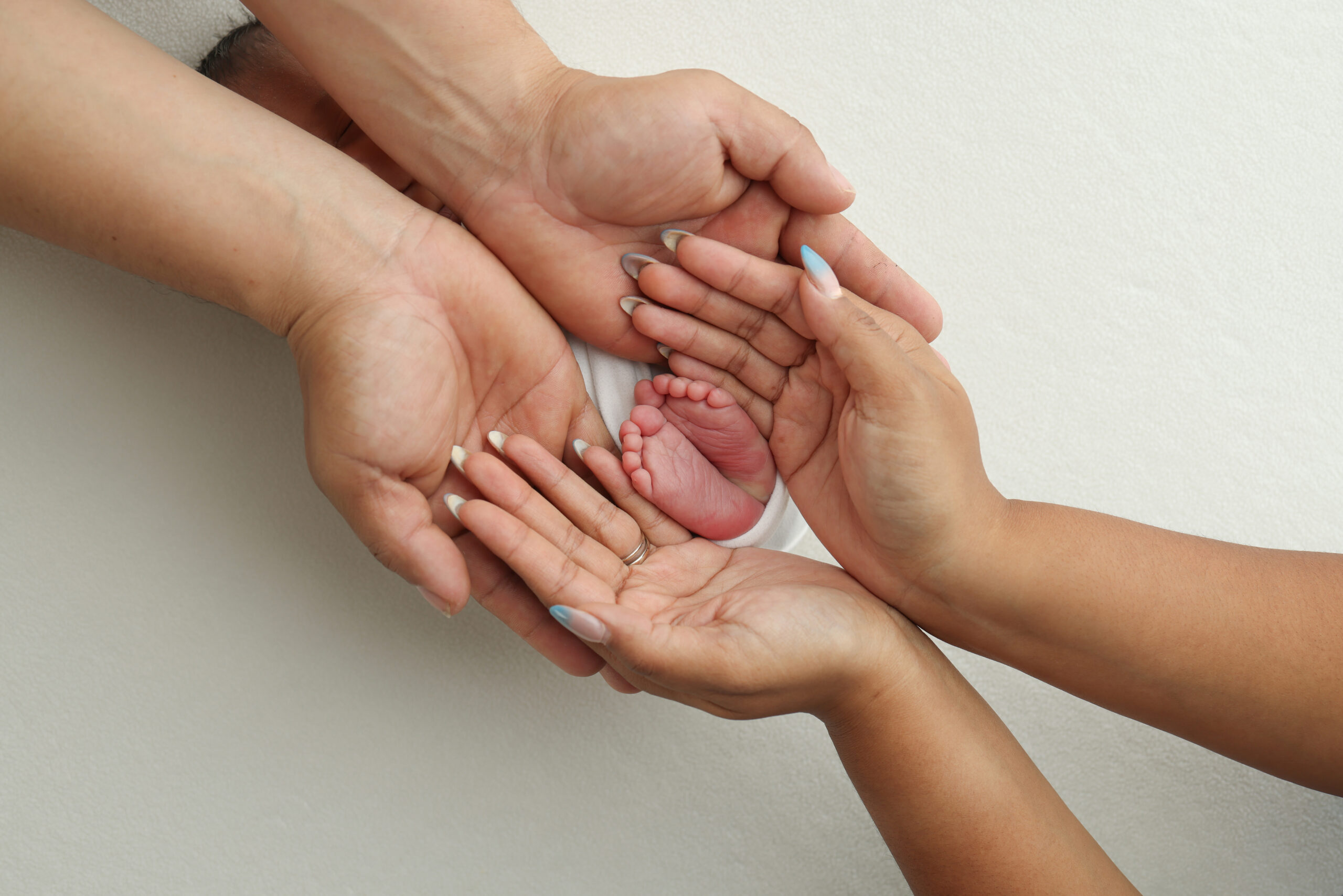 Man and woman's hands holding their baby's feet
