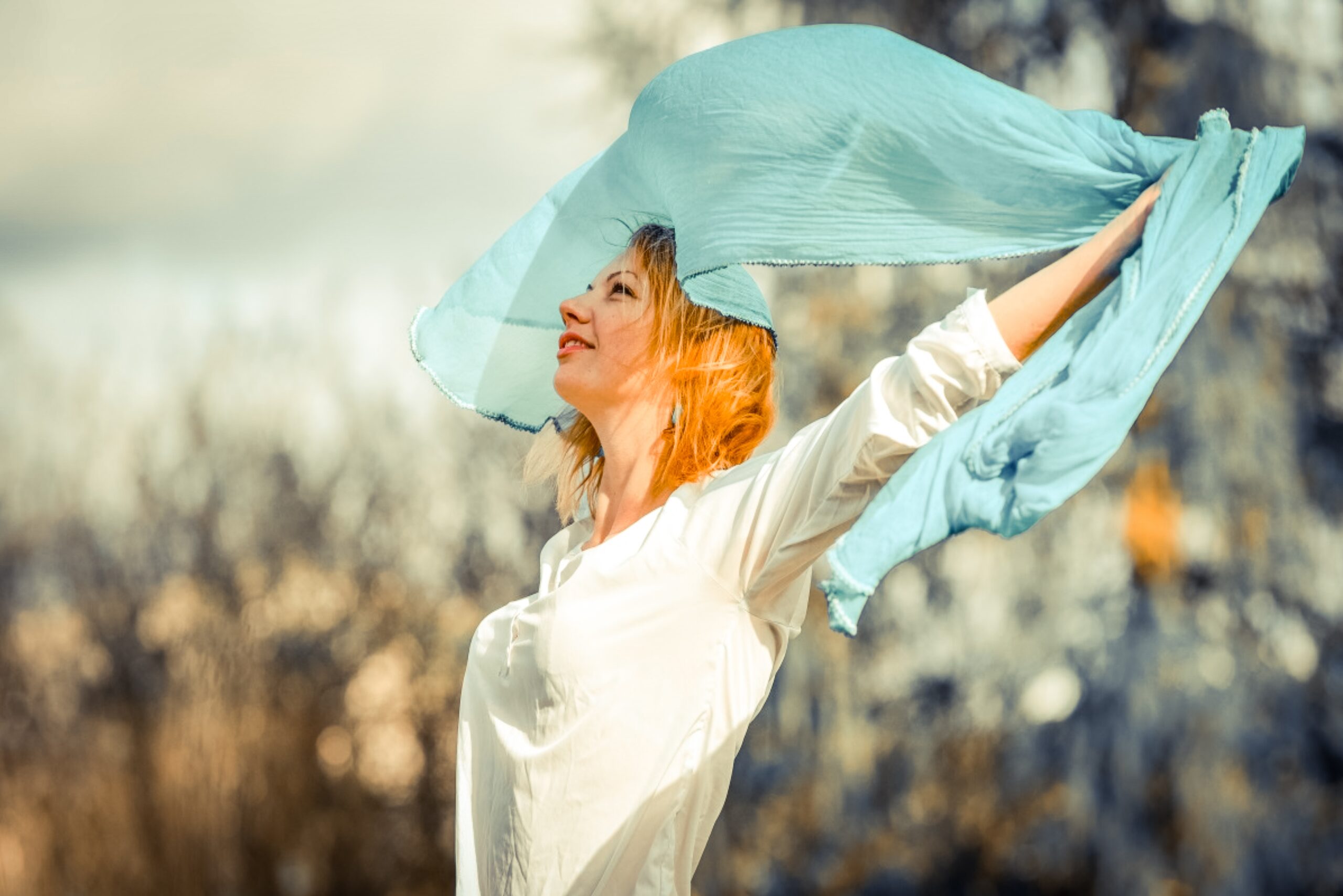 Woman in a white shirt holding a blue scarf in the air