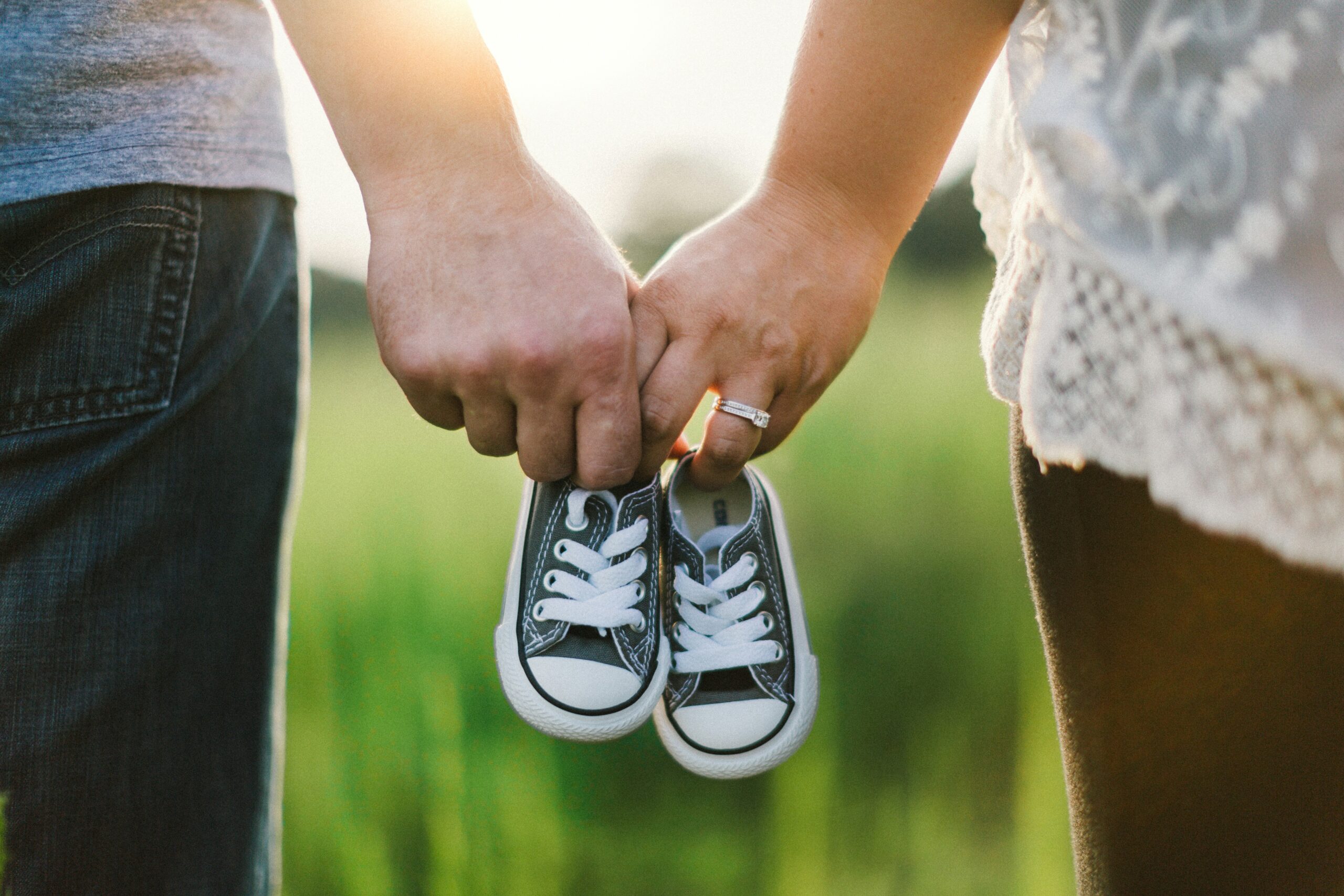 Man and woman's hands holding baby sneakers